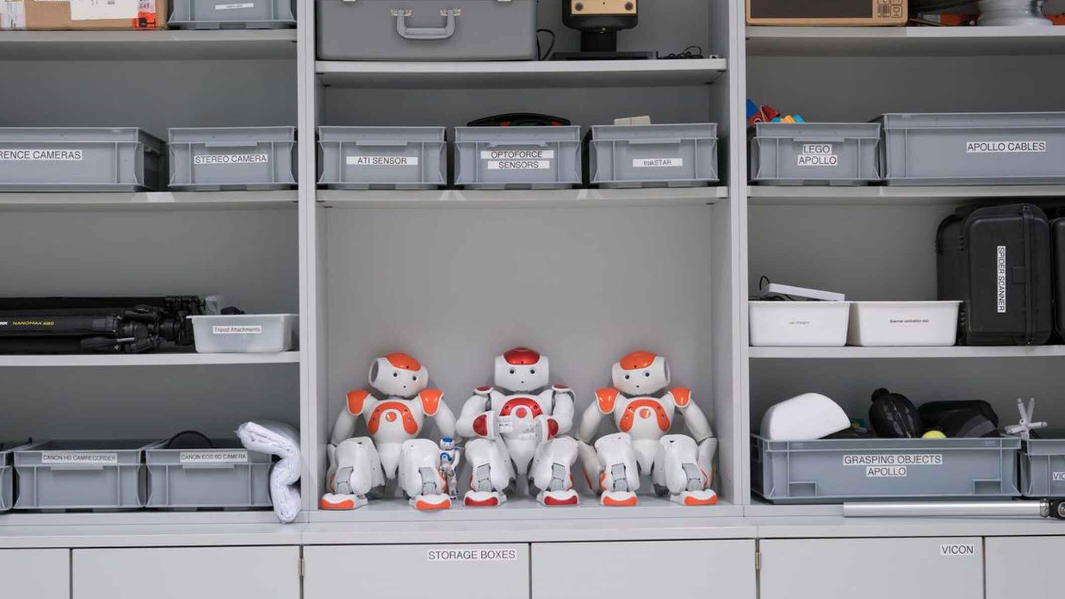 A humanoid robot named Nao is waiting in the spare parts cabinet of the robotics group for researchers to program it.