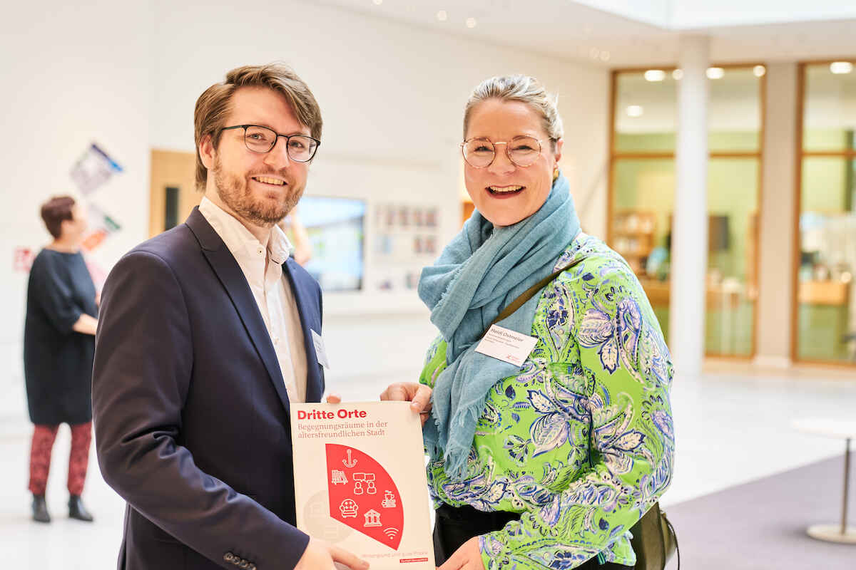 David Menn (Körber-Stiftung) überreicht Heidi Ostmeier (Seniorenbeauftragte Stadt Gütersloh) die diesjährige Studie zu dritten Orten.